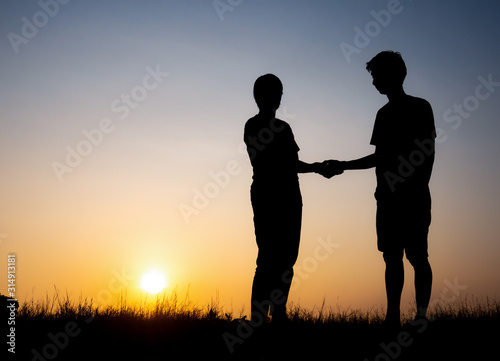 Silhouette of lovely couple holding by hands on beautiful sunset © showcake