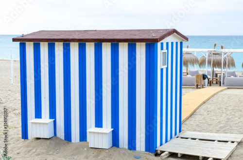White and blue striped beach house  warehouse for owners and operators of deckchairs and umbrellas on the beach in Marbella Andalucia Spain. Beautiful and freshly painted decorated warehouses