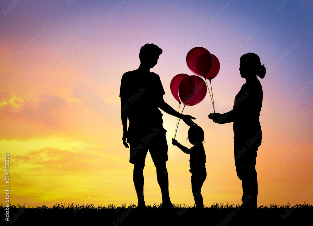 Silhouette family,father, mother and children holding balls against the sunset.