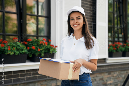 Crop of deliverywoman holding parcel and folder. photo