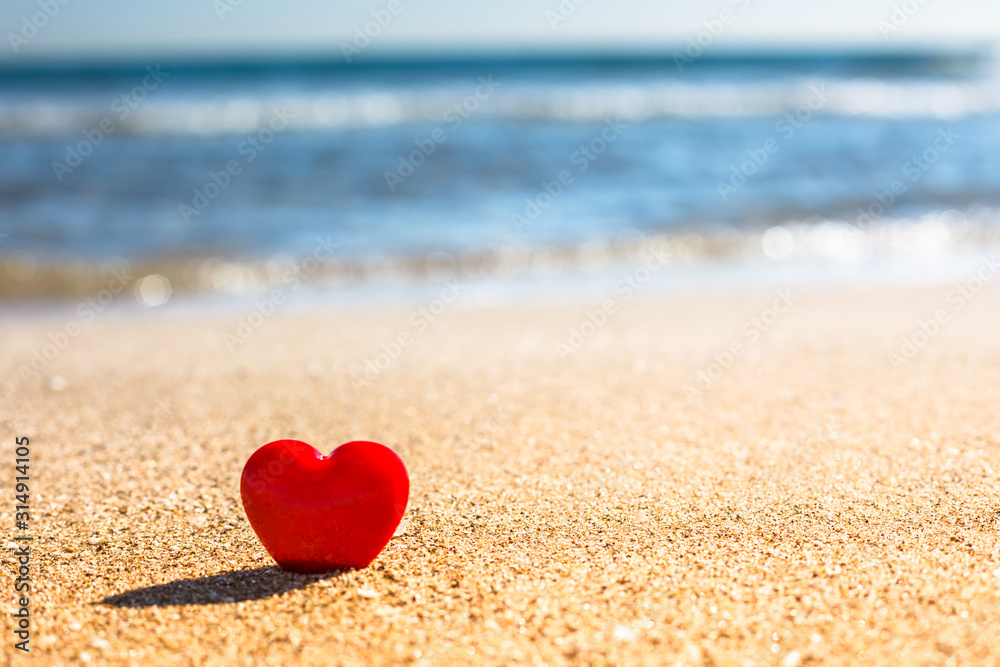 Romantic symbol of red heart on the sand beach