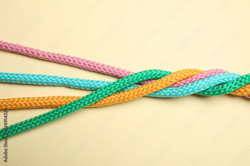 Twisted colorful ropes on beige background, top view. Unity