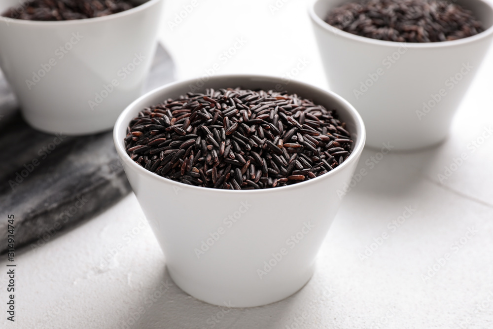 Uncooked brown rice in bowl on white table, closeup Uncooked brown rice in bowl on white table, closeup