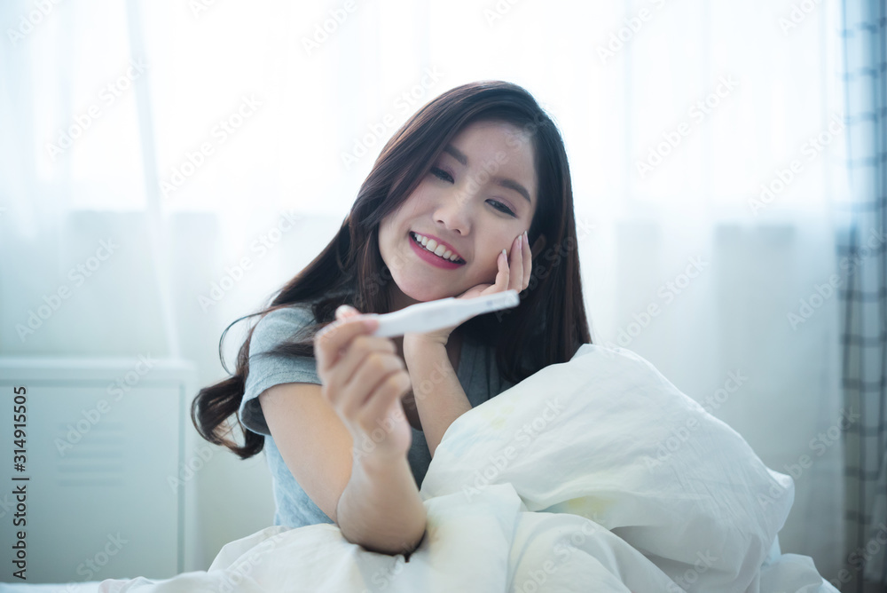 young woman taking a pregnancy test and smiling young woman taking a pregnancy test and smiling