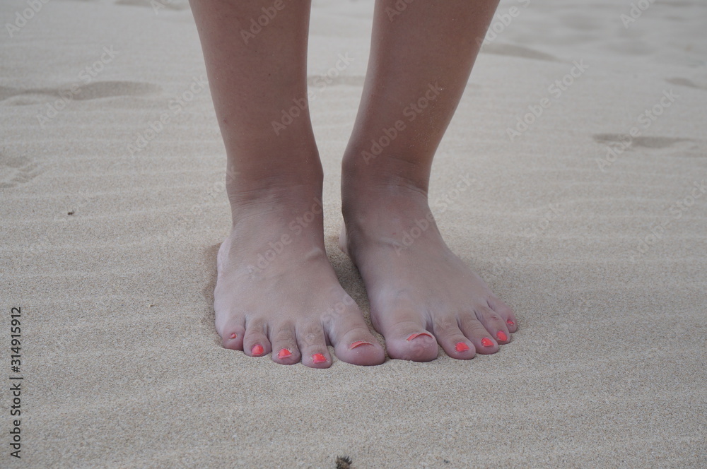Women's feet on the beach near the sea. The girl took a picture of his feet on the background of sand by the ocean, copy space. Women's feet on the beach near the sea. The girl took a picture of his feet on the background of sand by the ocean, copy space.