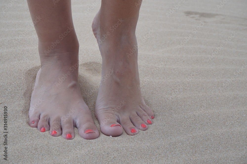 Women's feet on the beach near the sea. The girl took a picture of his feet on the background of sand by the ocean, copy space. Women's feet on the beach near the sea. The girl took a picture of his feet on the background of sand by the ocean, copy space.