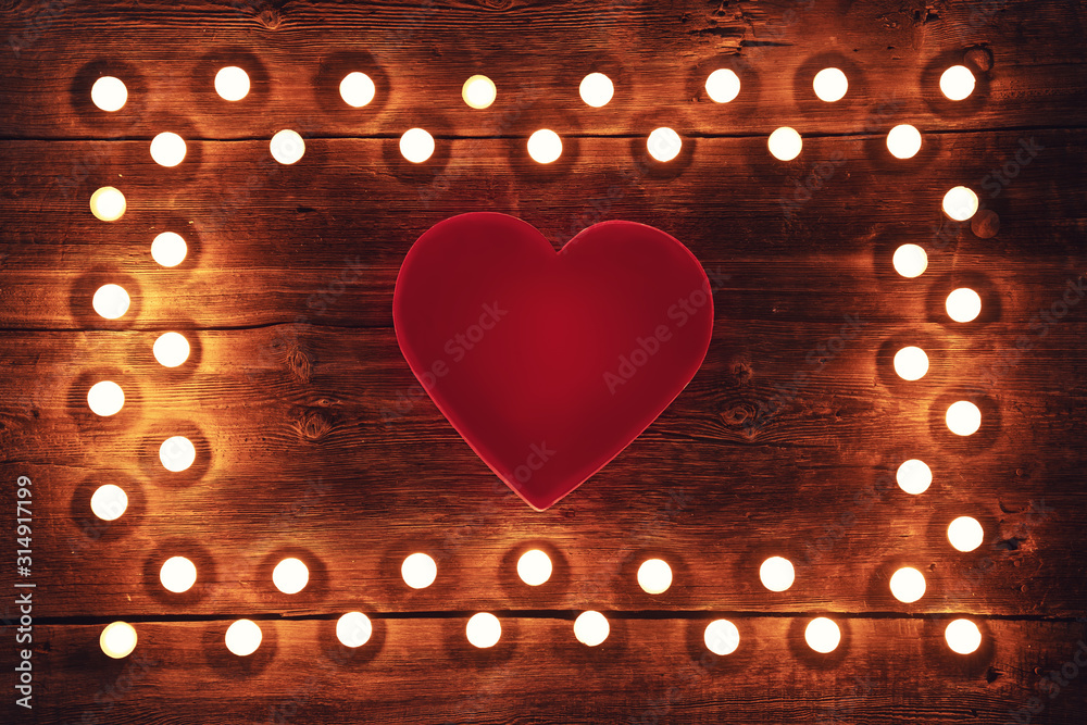 Vintage wooden background with tea light candles border and red heart shape, valenitnes day concept.