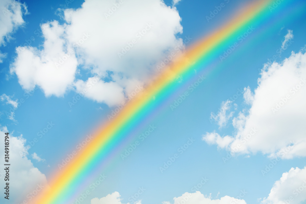 rainbow in the blue sky surrounded by clouds rainbow in the blue sky surrounded by clouds