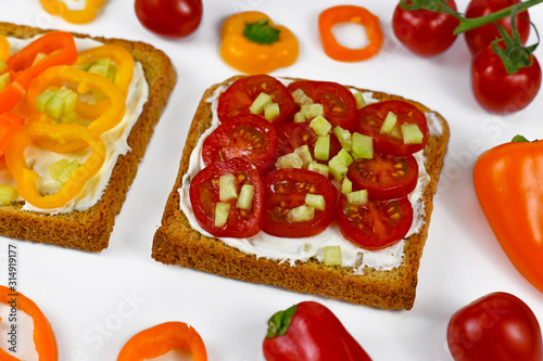Slice of healthy whole grain toast topped with cherry tomatos and cucumber pieces
