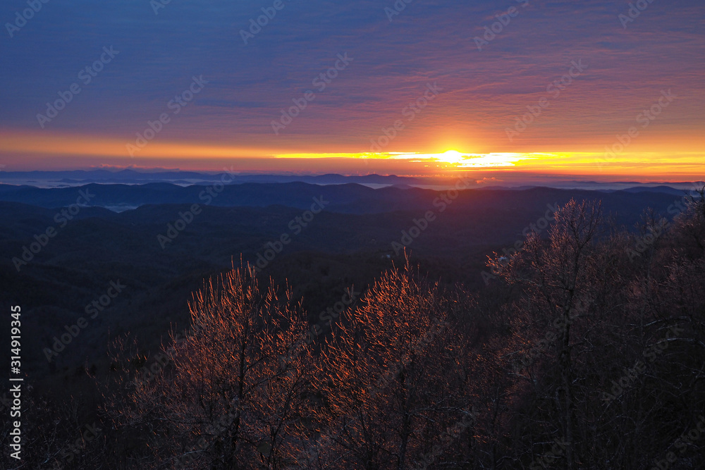 Fototapeta premium Colorful sunrise over layered mountains after ice storm in Blowing Rock, North Carolina.