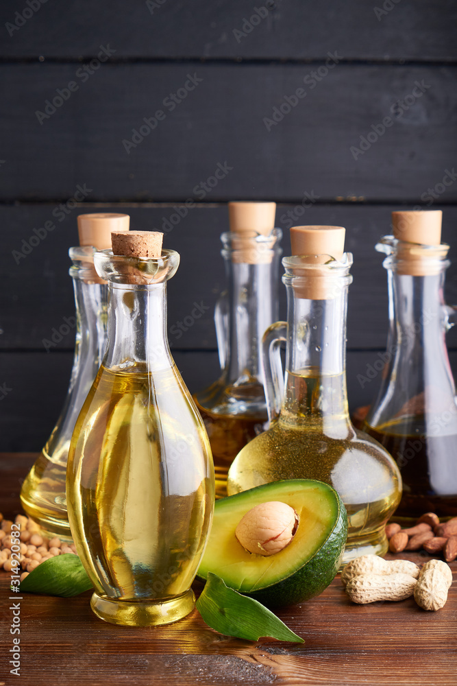 Useful vegetable oils in glass bottles. Avocado oil, chickpea oil, linseed oil, peanut oil, almond oil. Dark wooden background Useful vegetable oils in glass bottles. Avocado oil, chickpea oil, linseed oil, peanut oil, almond oil. Dark wooden background