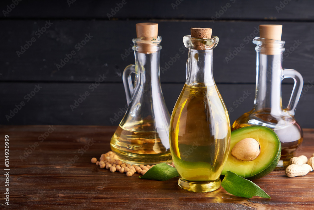 Healthy vegetable oils in glass bottles. Avocado oil, chickpea oil, peanut oil, almond oil. Dark background Healthy vegetable oils in glass bottles. Avocado oil, chickpea oil, peanut oil, almond oil. Dark background