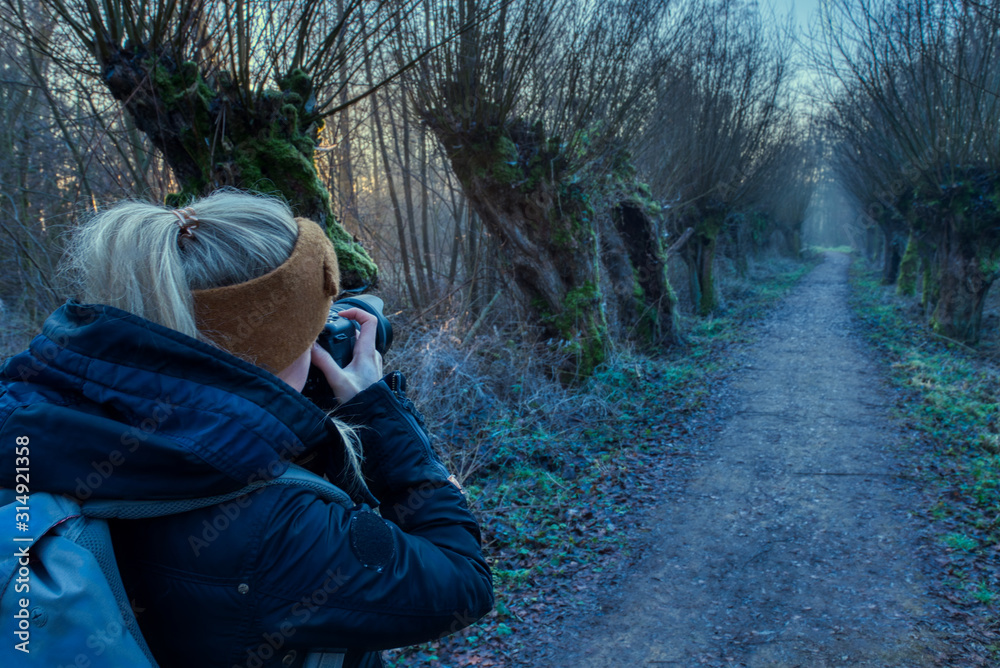 Blond girl photographing mystic path through the forest Blond girl photographing mystic path through the forest