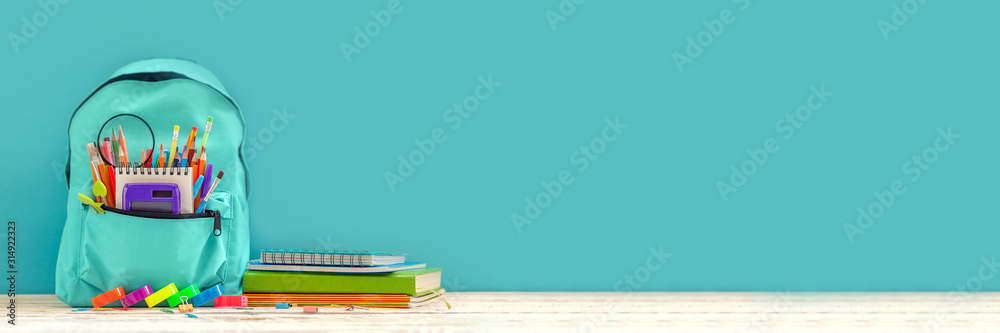 Concept back to school. Full turquoise School Backpack with stationery on table. Banner. - obrazy, fototapety, plakaty 