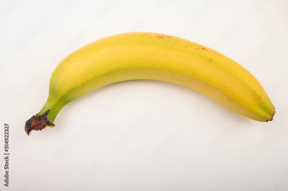 One ripe yellow banana on a white background. Close up.