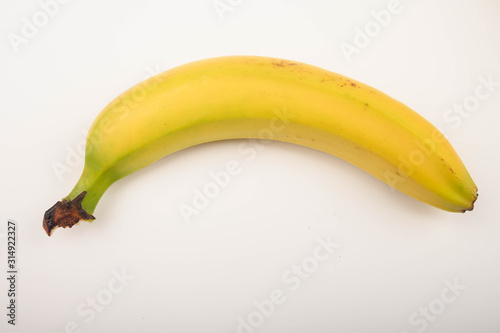 One ripe yellow banana on a white background. Close up.