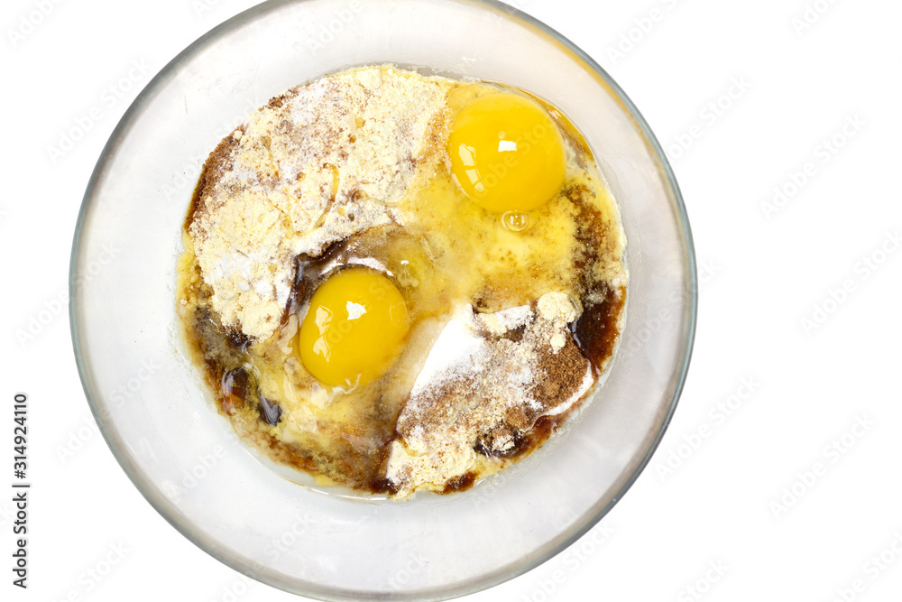 Corn and rice flour, coconut sugar, two eggs in the transparent plate. Making a cake. Mixing the dough. White background. Copy space. Place for text and design. Top view. Flat lay. Corn and rice flour, coconut sugar, two eggs in the transparent plate. Making a cake. Mixing the dough. White background. Copy space. Place for text and design. Top view. Flat lay.