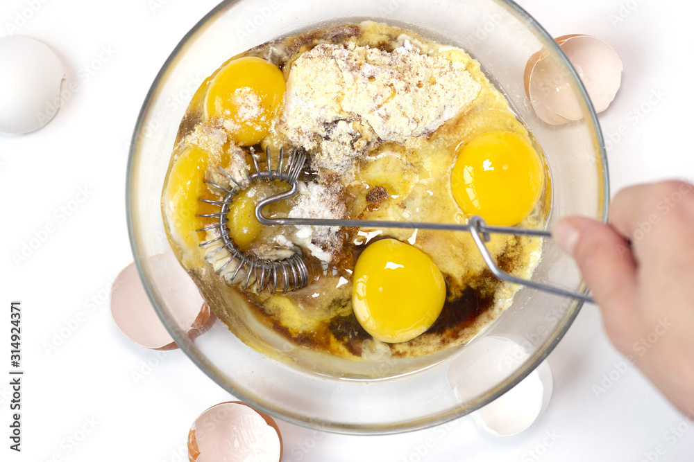 Corn and rice flour, coconut sugar, four eggs in the transparent plate. Making a cake. Mixing the dough. White background. Copy space. Place for text and design. Top view. Flat lay. Gluten-free recipe Corn and rice flour, coconut sugar, four eggs in the transparent plate. Making a cake. Mixing the dough. White background. Copy space. Place for text and design. Top view. Flat lay. Gluten-free recipe