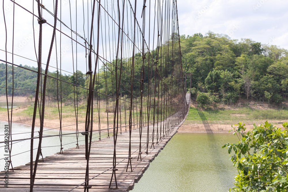 Obraz premium Suspension bridge on the river With mountains and sky in the background