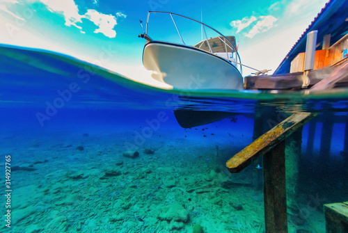 Over under view of seabed scuba diving boat and dock