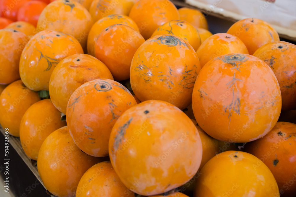 orange ripe persimmon korolek on a market counter