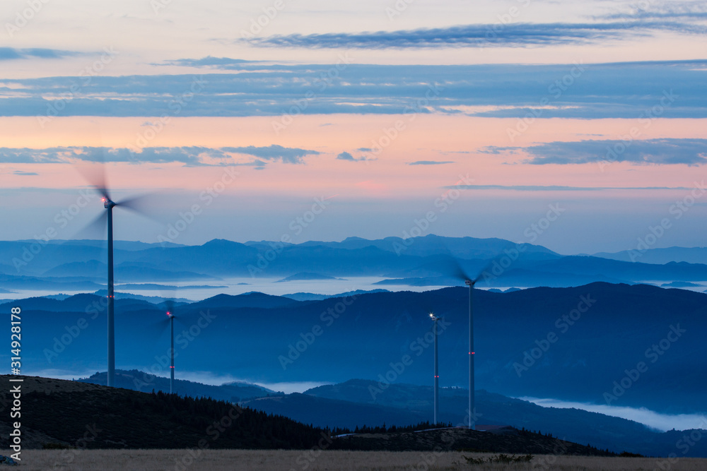 Wind turbines on the mountain morning fog at sunset Wind turbines on the mountain morning fog at sunset