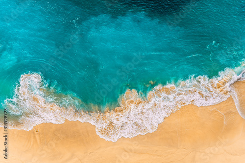 Fototapeta Naklejka Na Ścianę i Meble -  Aerial view of turquoise ocean waves in Kelinking beach, Nusa penida Island in Bali, Indonesia. Beautiful sandy beach with turquoise sea. Lonely sandy beach with beautiful waves. Beaches of Indonesia
