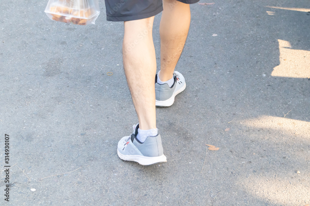 Backside view of person which walk on the concrete road.