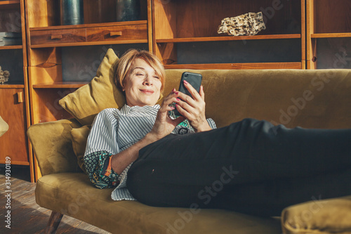 Senior lady with smart phone resting at home photo