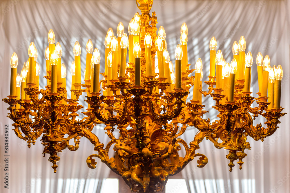 Chandelier in front of window with white curtain. Electric drop-shaped bulb. Chandelier in front of window with white curtain. Electric drop-shaped bulb.