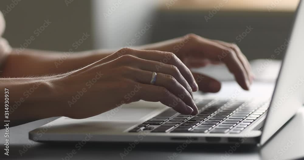 Female hands typing on laptop at desk, close up view