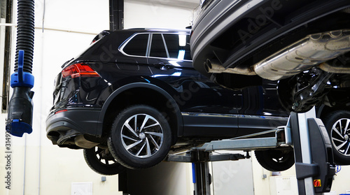 A modern car SUV in a service center is lifted on a lift for diagnosis, maintenance or repair. New shiny expensive off-road car in service. Concept.  © Орлов Александр