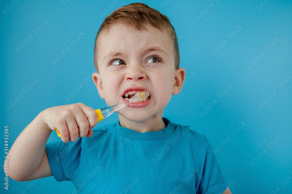 Little cute boy brushing his teeth on blue background Little cute boy brushing his teeth on blue background