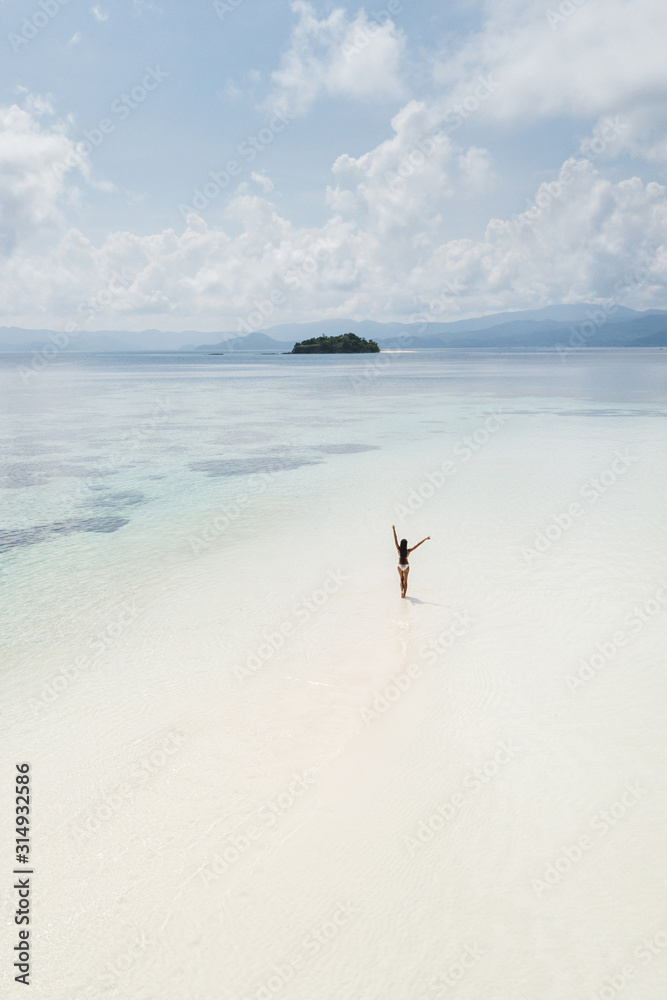 Woman walking alone on amazing tropical white sand beach. Aerial drone view from above. Tropical background and travel concept.