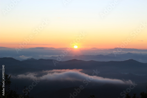 Beautiful scenery of mountain with mist sea, golden light shines on sky and sunrise up from the horizon at view point of Phu chi phoe in the early morning, Khun Yuam, Mae Hong Son, Thailand © Stella