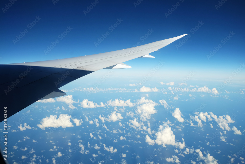 View from airplane window with sky and white clouds at noon View from airplane window with sky and white clouds at noon