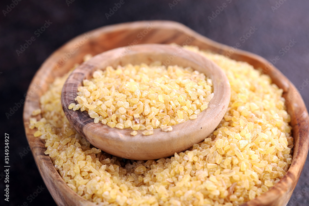 Uncooked bulgur in wooden spoon, rustic style. Healthy Bulgur wheat grains Uncooked bulgur in wooden spoon, rustic style. Healthy Bulgur wheat grains
