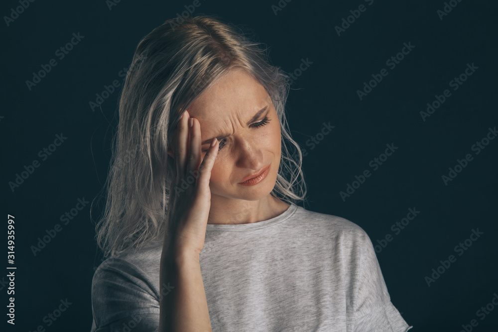 Young model with migraine in the dark studio isolated