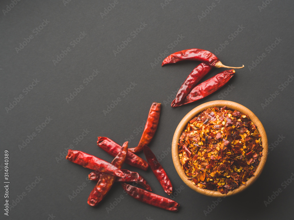 Φωτογραφία Chili flakes in the wooden bowl and dried peppers on black papper background