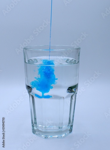 Glass of water with burst of blue color from water enhancer
