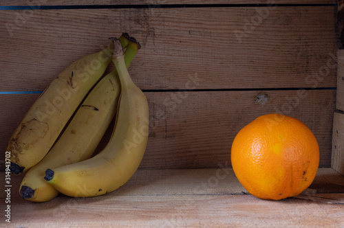 Banana branch and orange. Multivitamins. Yellow fruits. Fruit in a box.