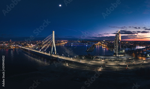 Aerial view over Riga city at night time. Urban landscape with skyscrapers and highway with city lights.
