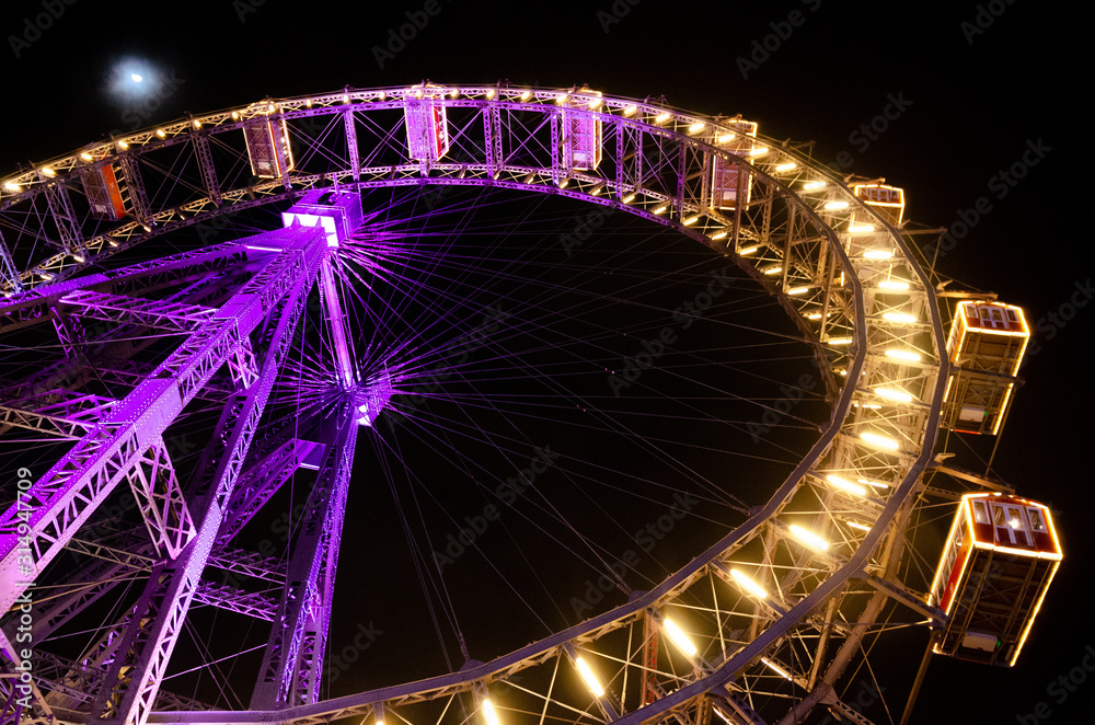 Night view of a Big Wheel lit with pink violet and golden lights