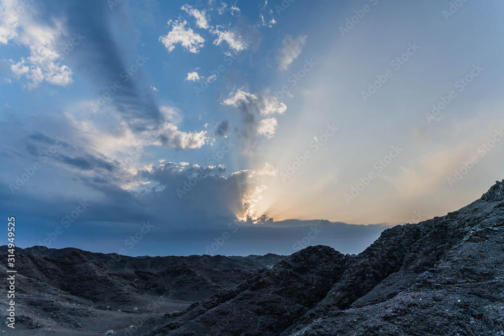 Naklejka premium Scenic Sunset Sky with Strong Sunbeam and Cloudy Sky over Rocky Mountains Island