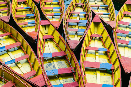 Pattern of red and yellow wooden boats moored next to eah other on Phewa lake in Pokhara, Nepal photo