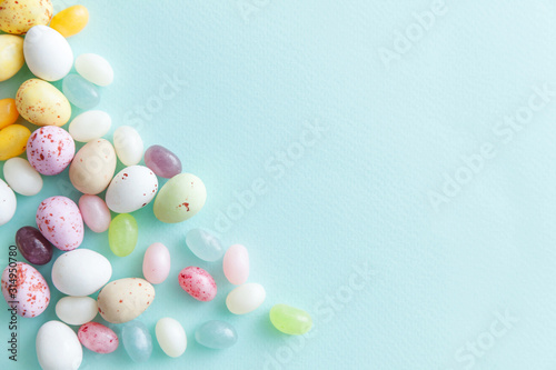 Happy Easter concept. Preparation for holiday. Easter candy chocolate eggs and jellybean sweets isolated on trendy pastel blue background. Simple minimalism flat lay top view copy space.