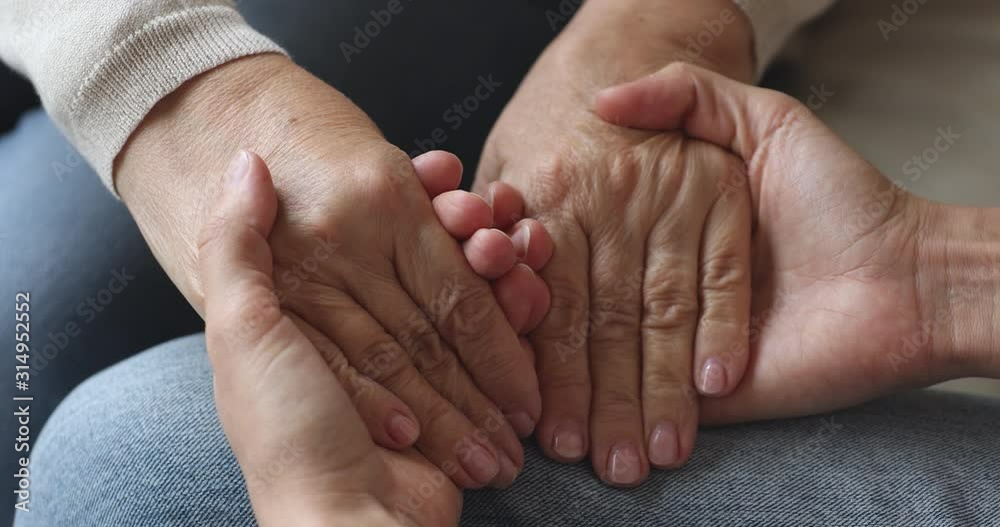 Young woman hold old female hands giving support concept, closeup