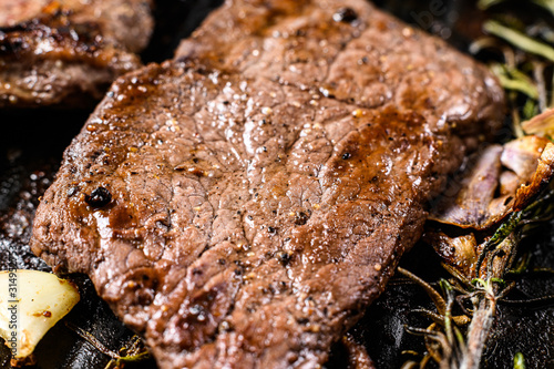 Sirloin steak in a frying pan. Grilled meat. Black background. Top view © Vladimir