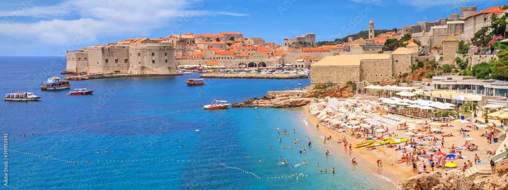 Coastal summer landscape - view of the city beach on the background of the Old Town of Dubrovnik on the Adriatic coast of Croatia