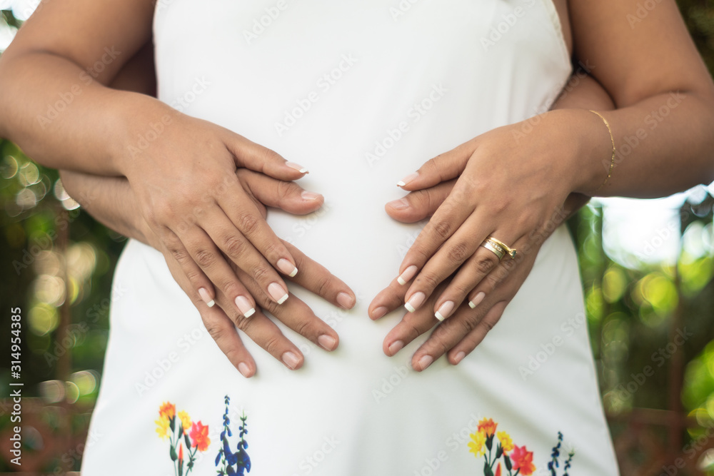 Hands on a belly of a beautiful pregnant woman in nature Hands on a belly of a beautiful pregnant woman in nature